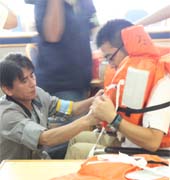 救命胴衣の着用を説明する乗組員